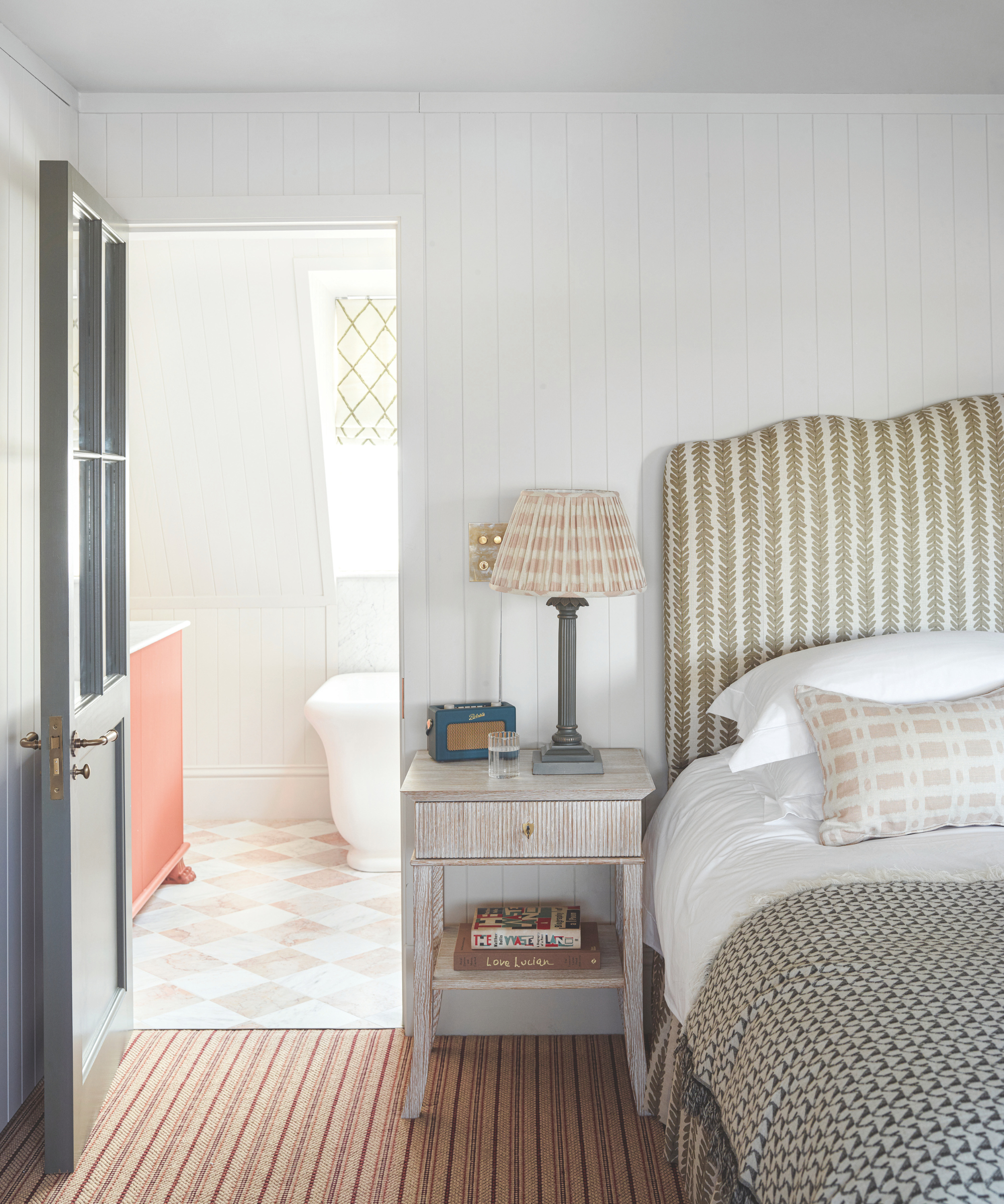 a bedroom with a bedside table and a door to a bathroom