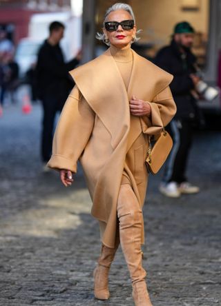 Grece Ghanem wearing a camel coat with over-the-knee camel boots.