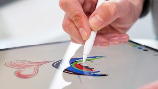 En hånd bruger en Apple Pencil til at tegne på en skærm