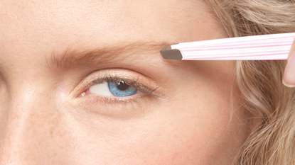 Best tweezers - close up of a woman using tweezers to pluck her eyebrows