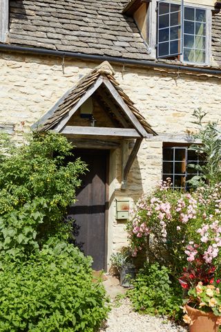 a thatched cottage porch hedges and flowers by the door