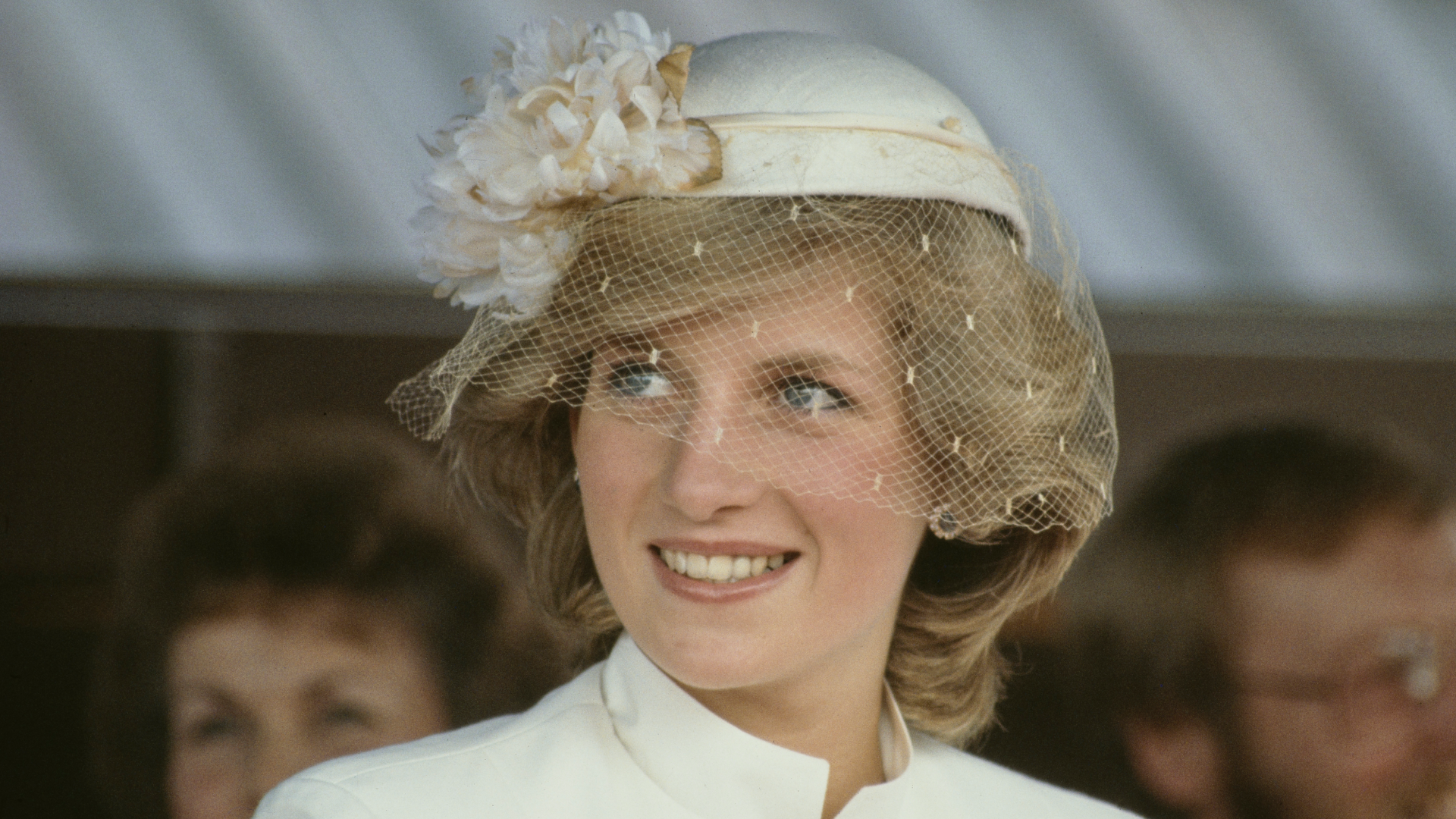 Princess Diana wearing a white veiled hat and smiling