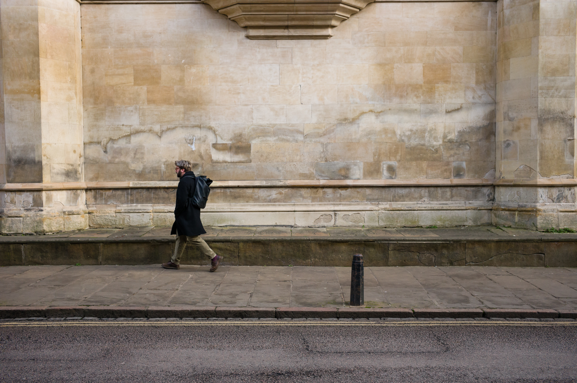 A person walking in front of a wall shot on the Leica M11
