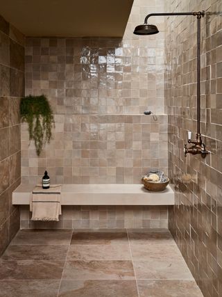 Cream green zellige tiles with a seating area and brass shower fixtures