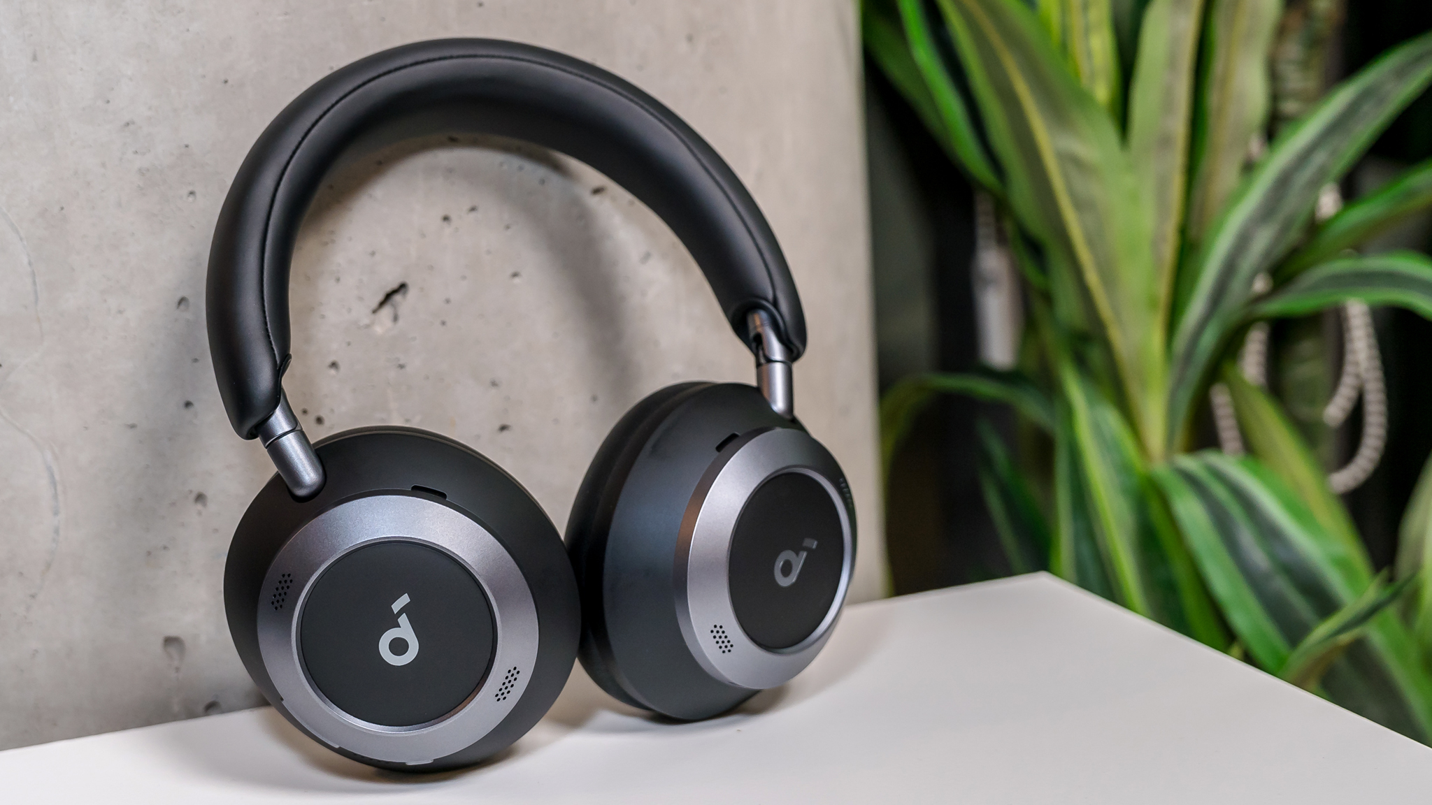 Anker Soundcore Space One Pro headphones leaning upward on a table and wall.