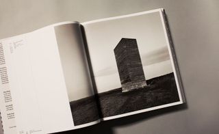 A open book with an image of the Bruder Klaus chapel in Mechernich, Germany. A vertical rectangular structure in a field.