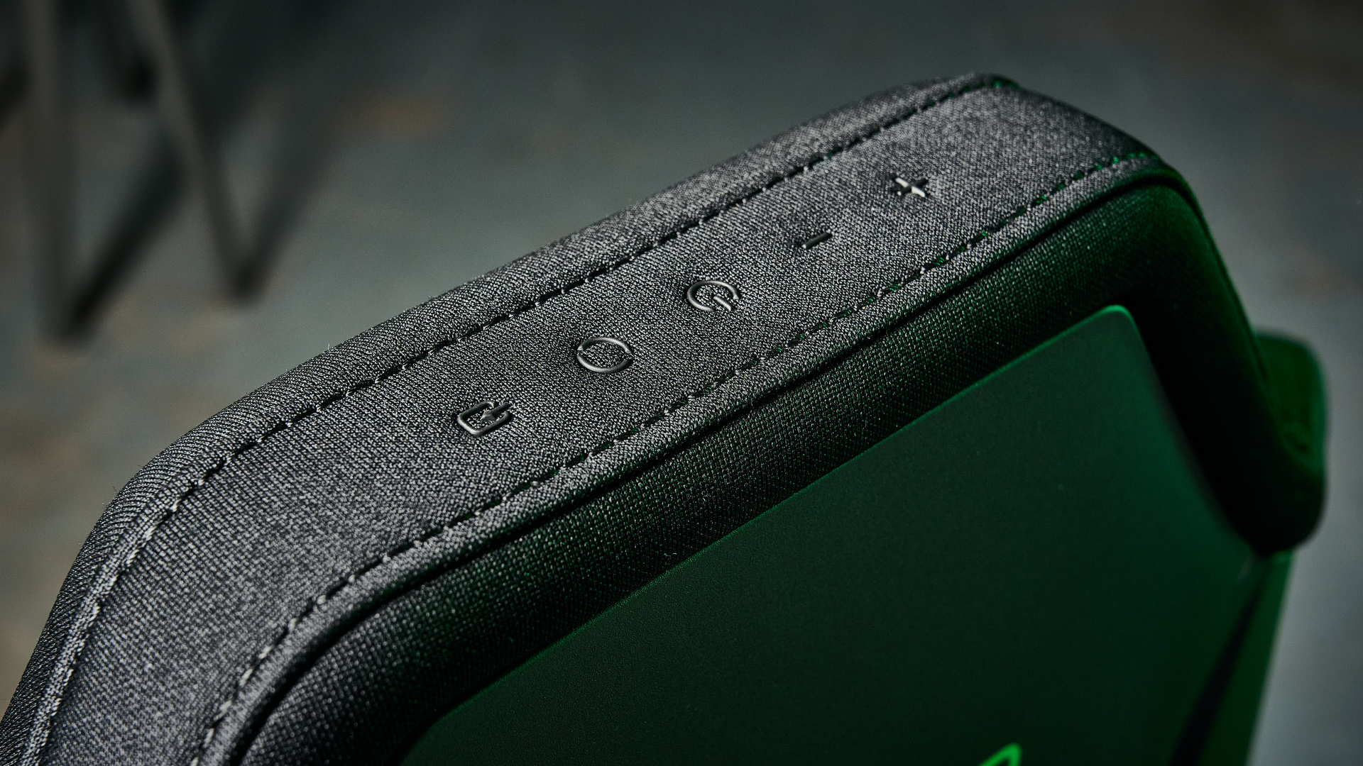 The Razer Soma Chroma chair top controls, illuminated by a green glow