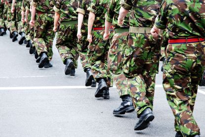 An image of several army personnel marching in a line, the image focuses on their boots. 