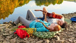 sleeping pad vs air mattress: couple having a guitar singalong on a sleeping pad