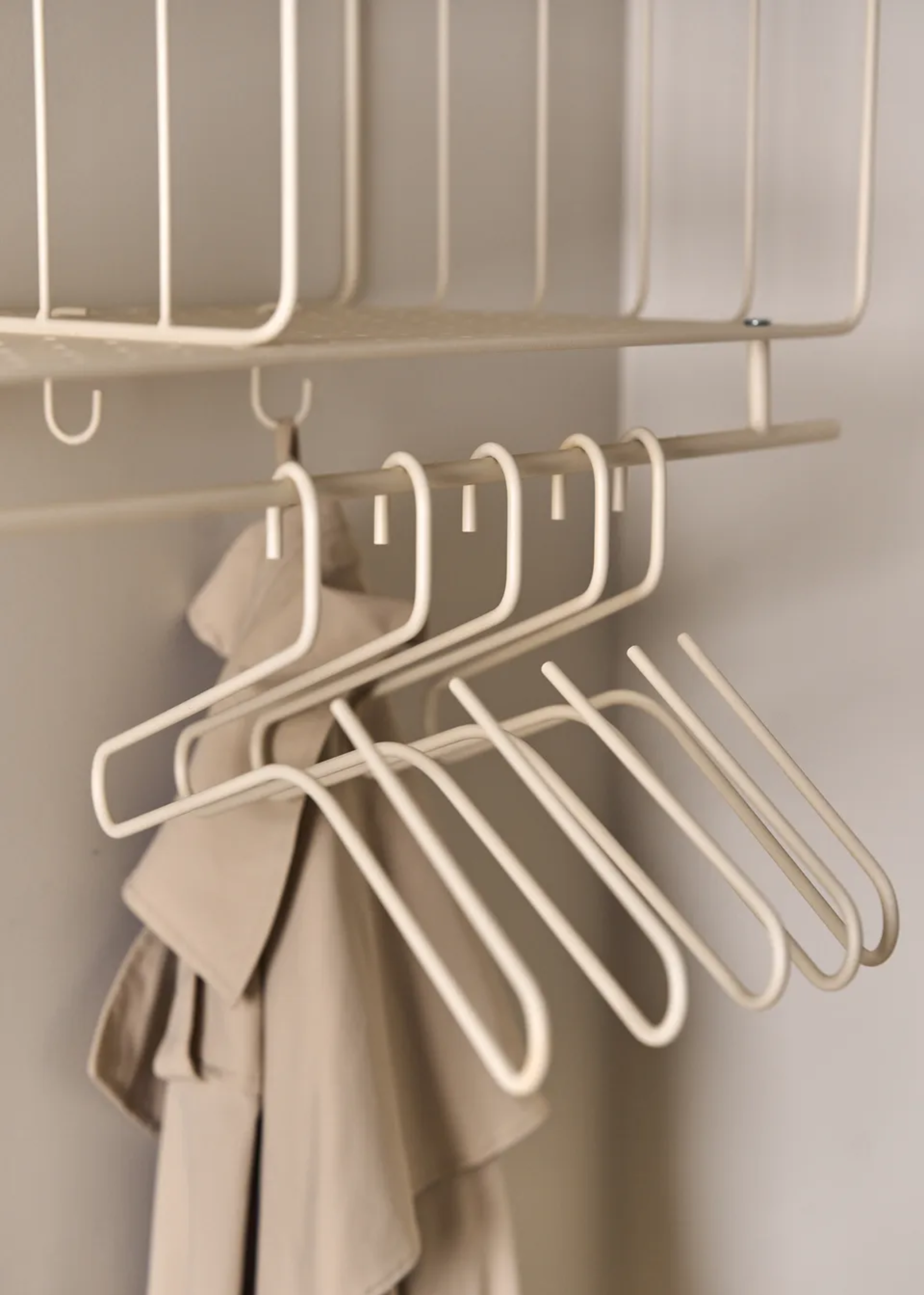 A wardrobe with beige structural clothes hangers on a rung