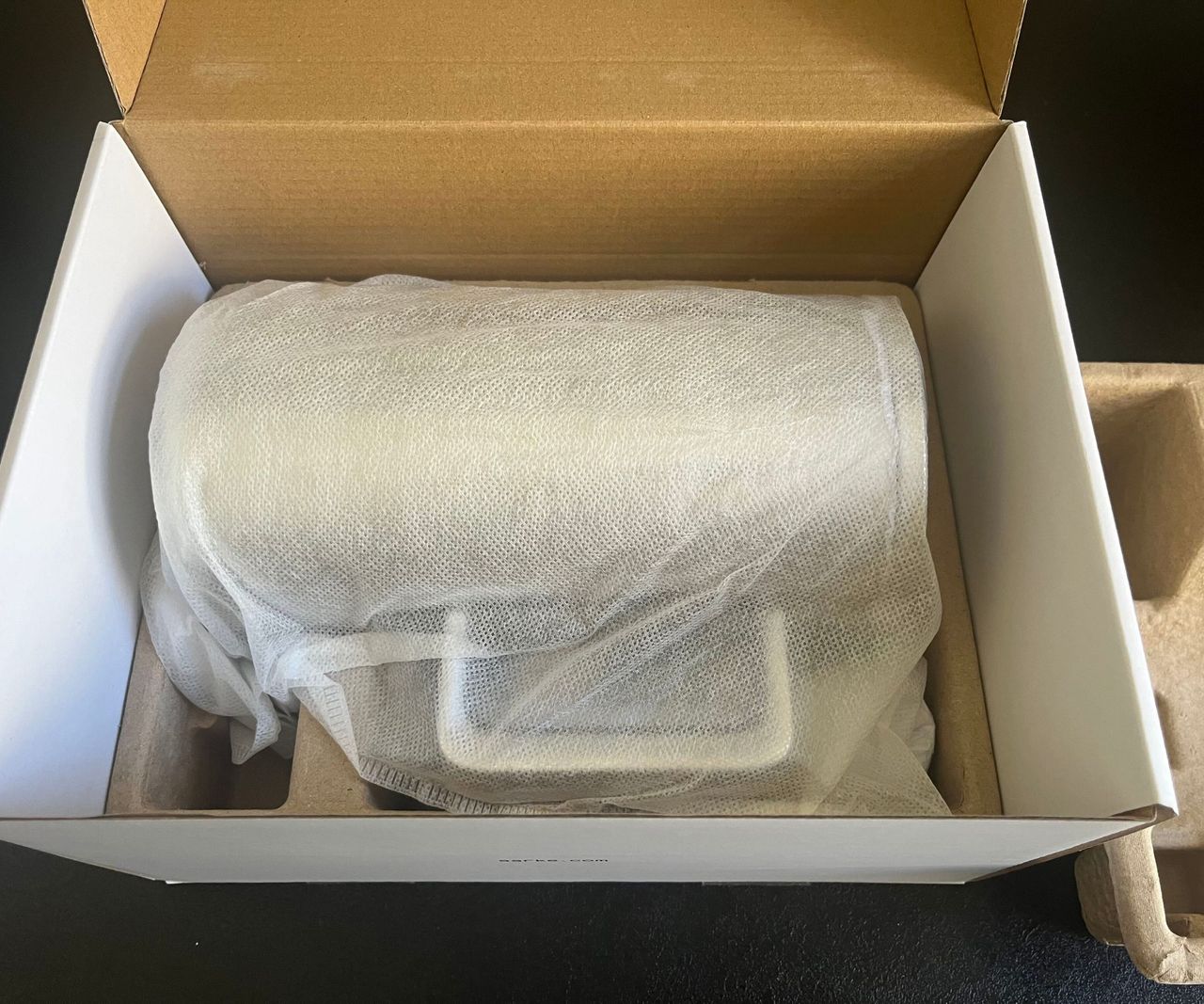 The aarke coffee press in a thin cotton bag inside a cardboard box.