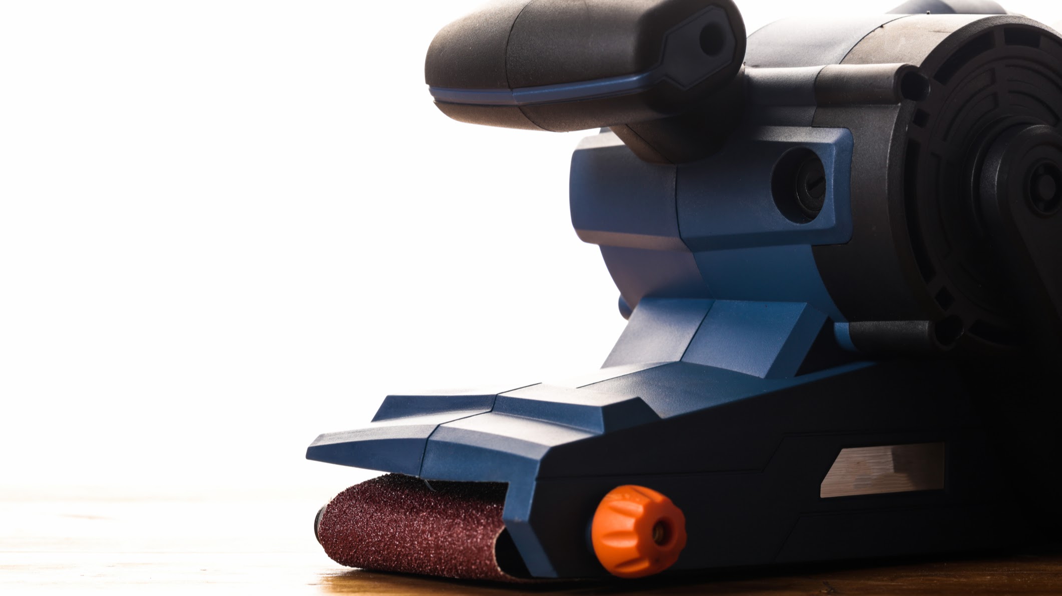 A belt sander on a wood floor surface