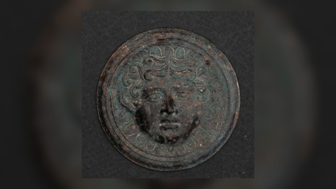 This image shows a mermaid head within a circle of bronze. It was found on a bronze bed unearthed in the ancient burial of a woman lying near the city of Kozani in northern Greece.