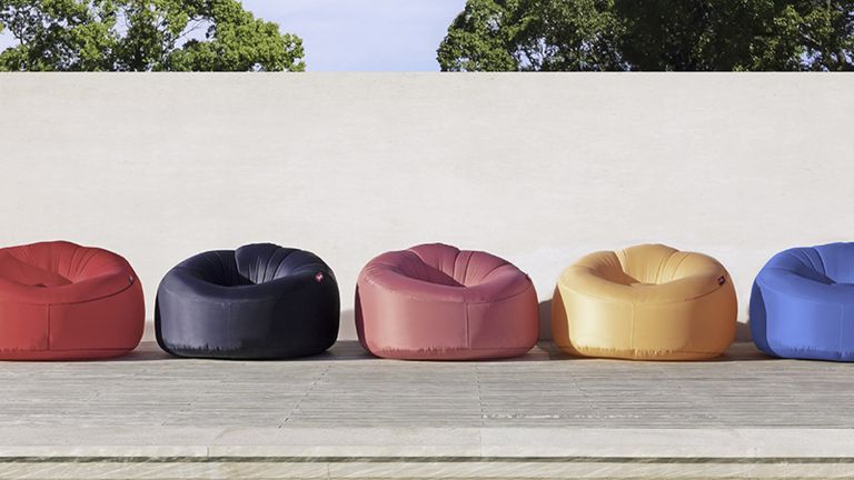 A row of multicoloured outdoor bean bags on a paved patio