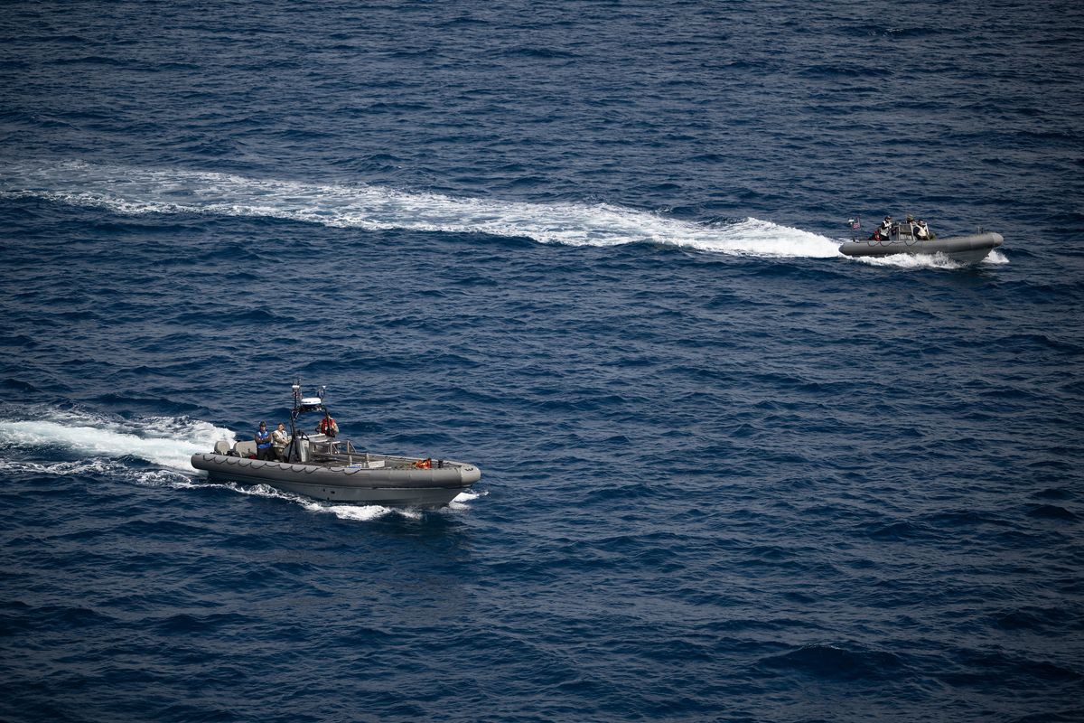 Small boats travel to the Orion capsule as part of Artemis 2 recovery efforts.