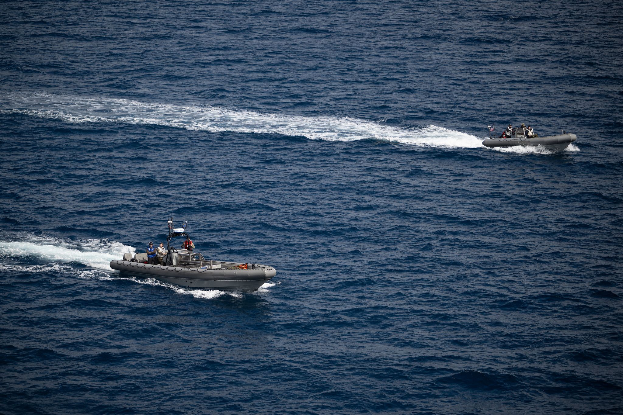 Small boats travel to the Orion capsule as part of Artemis 2 recovery efforts.