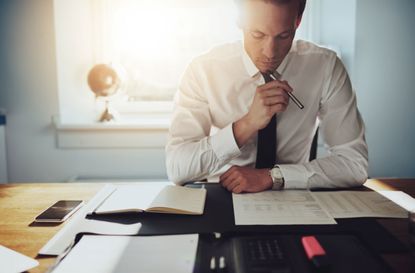 A man in a tie sits at a desk.