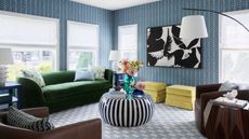 Living room with blue wallpaper, green couch and striped black and white coffee table 