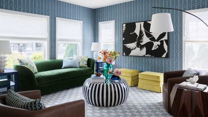 Living room with blue wallpaper, green couch and striped black and white coffee table 