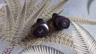 Sennheiser Momentum True Wireless 3 review: earbuds on a green pillow background