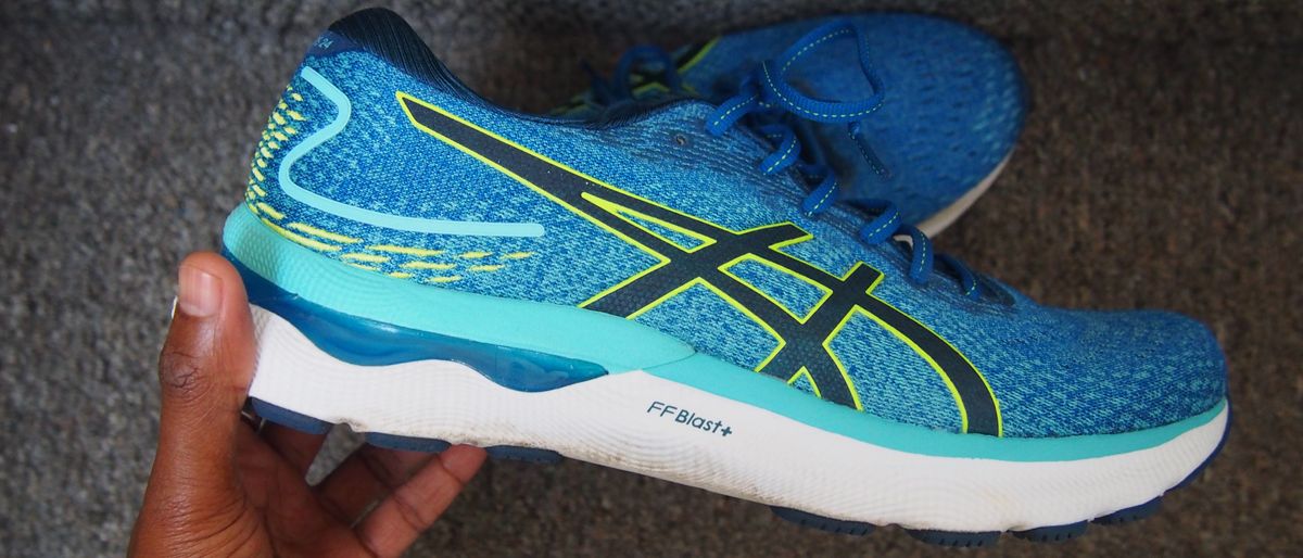 Man&#039;s hand holding Asics Gel Nimbus 24 running shoe in blue