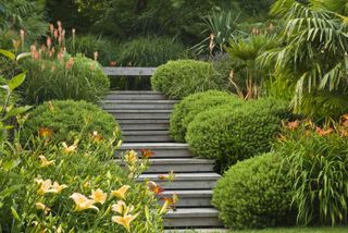sloping garden ideas: wooden steps leading up to a top patio area