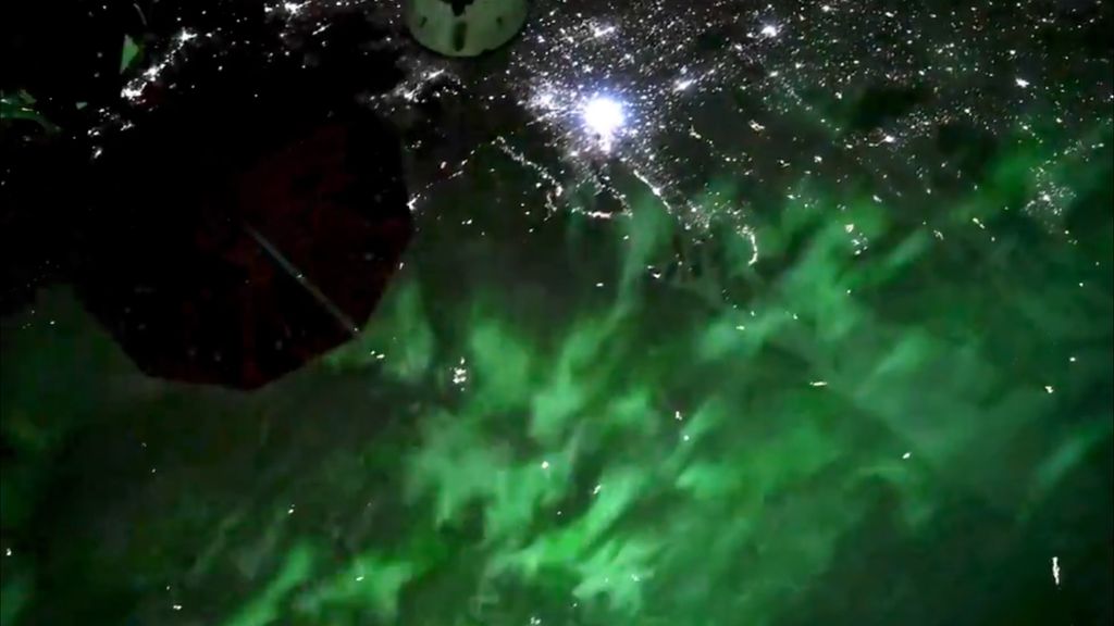 ISS astronaut captures green auroras dancing over city lights (video