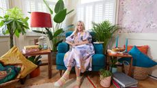 Fearne Cotton on blue armchair in living rom surrounding by bright soft furnishings, houseplants and trinkets