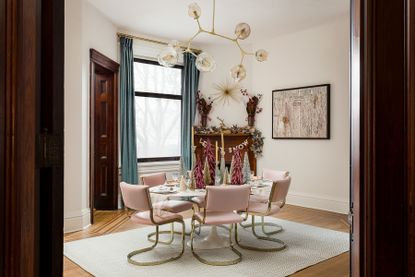 A dining room with pink chairs and plum toned trees on the table