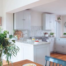 small grey kitchen with a mix of wall and floor cabinetry and marble splashback and wooden flooring
