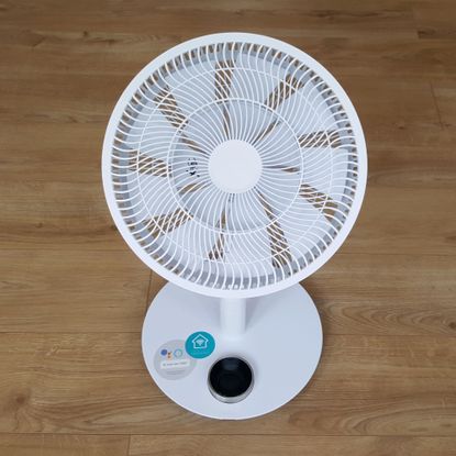 The white Duux Whisper Flex Ultimate Fan being assembled on a wooden floor