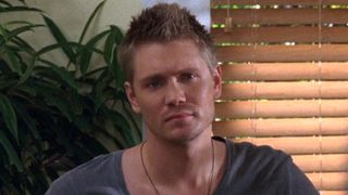 Lucas sitting down and looking serious on One Tree Hill.