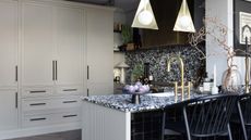 modern kitchen with terrazzo style counter and blackspash, brass edging and a gold tap