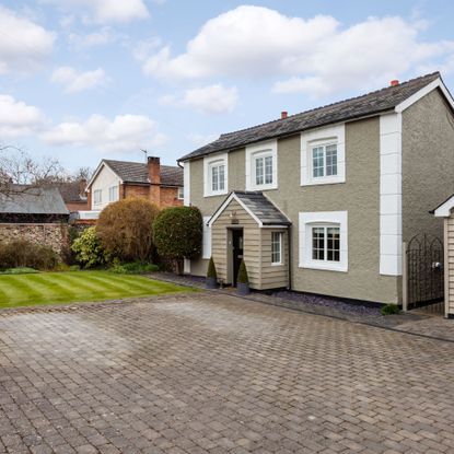 Block paving drive in front of house with clad porch and garage