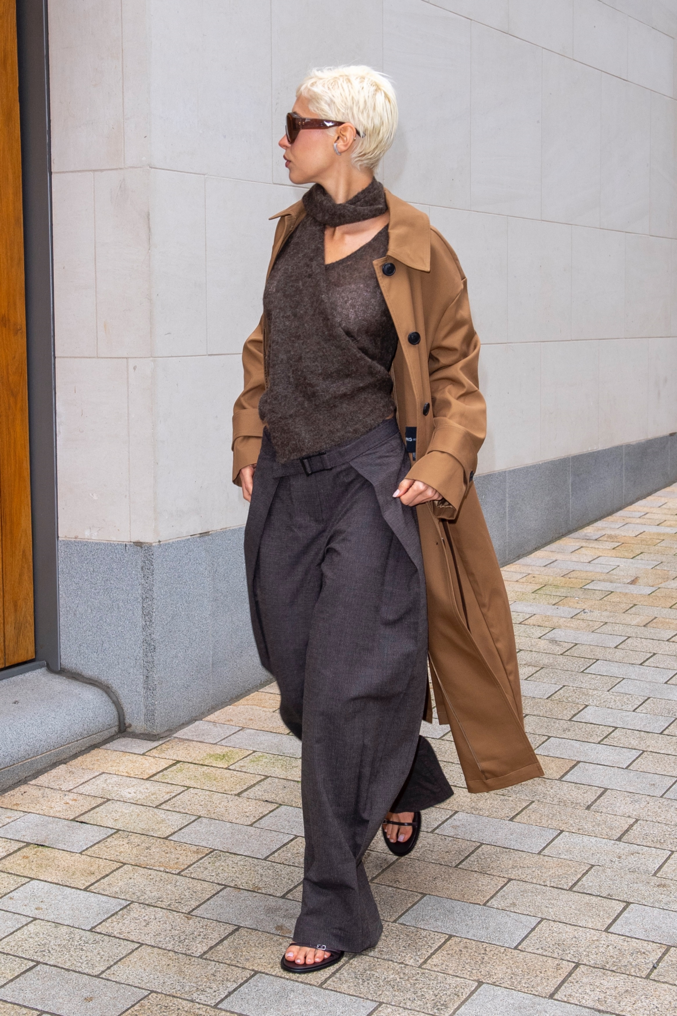 Iris Law arrived at London Fashion Week in pleated trousers, a brown trench coat, and a sweater from Mango