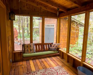 A swing bench in a screened in decked porch