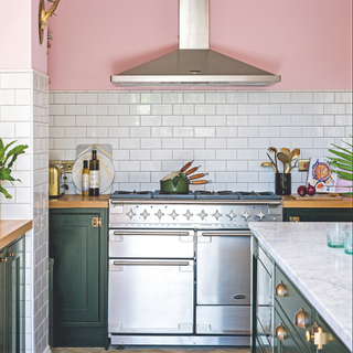 Open plan kitchen with pink walls, black Shaker style kitchen units, and rustic vintage furniture. Stainless steel range cooker. A kitchen project, the conversion of a basement to a kitchen diner in a five bedroomed Victorian house in Worthing, East Sussex, home of Jacquie and Ian Roebuck.