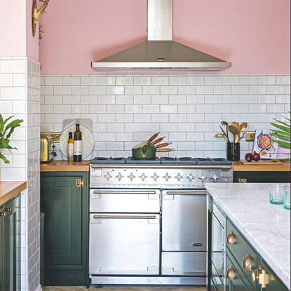 Open plan kitchen with pink walls, black Shaker style kitchen units, and rustic vintage furniture. Stainless steel range cooker. A kitchen project, the conversion of a basement to a kitchen diner in a five bedroomed Victorian house in Worthing, East Sussex, home of Jacquie and Ian Roebuck.