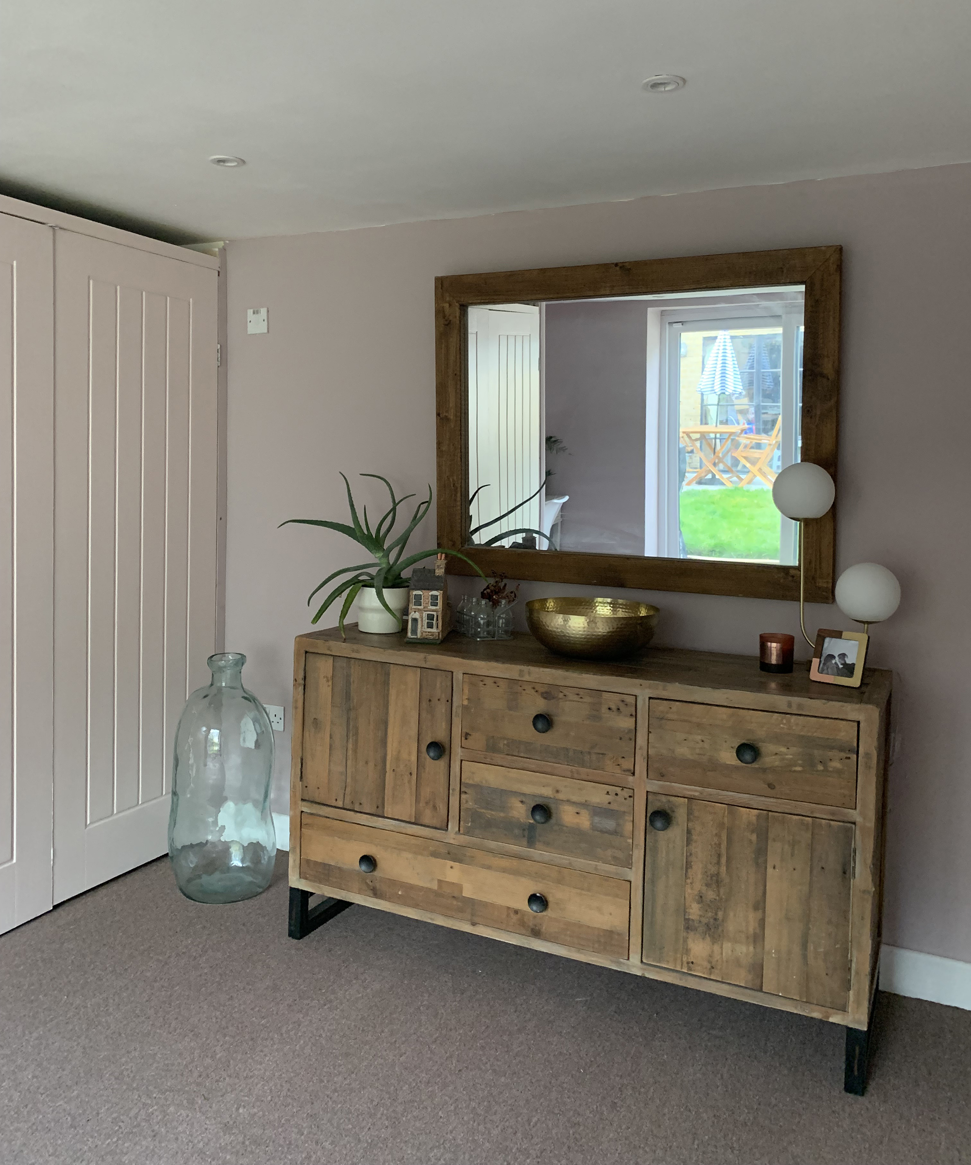 A backyard outbuilding with framed mirror, sideboard decor, and carpeted floor