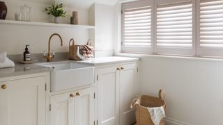 utility room with off white cabinets, butler sink and shutters at window