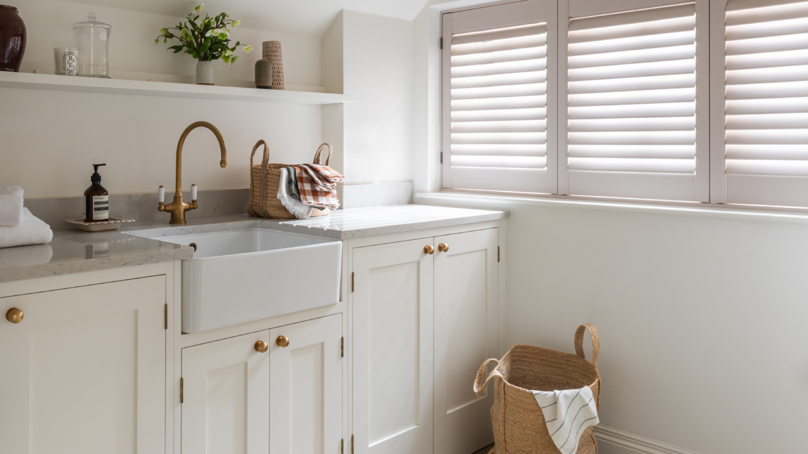 utility room with off white cabinets, butler sink and shutters at window