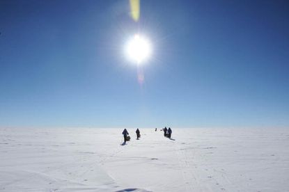 People walking on an ice sheet in Antarctica.