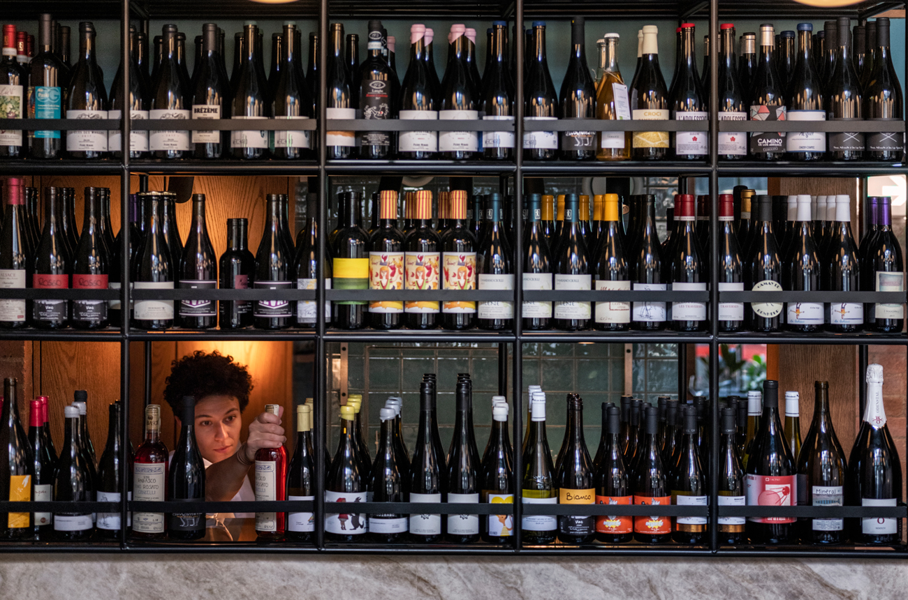 The wine wall at Flor with a sommelier selecting a bottle