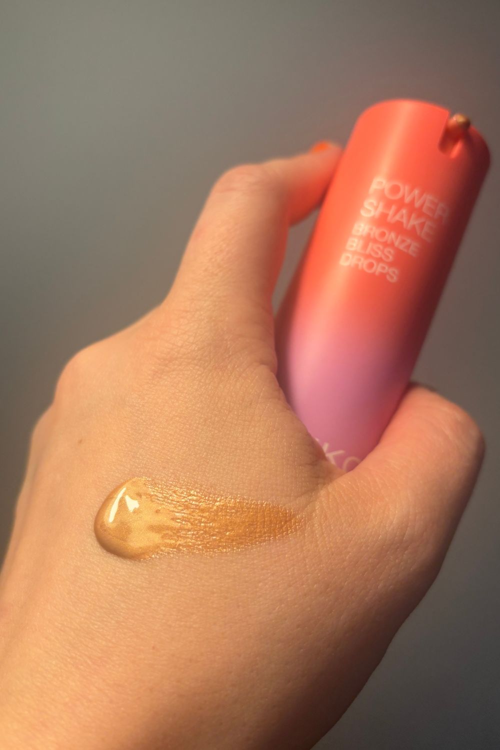 a hand holding a tube of kiko milano bronzing cream with a smear of product