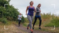 Women running in a group of three through wooded area smiling, wearing running clothes and training for a marathon