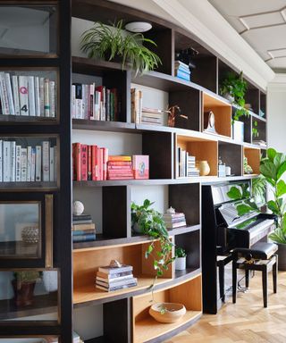modular open shelving with books, plants and an upright piano