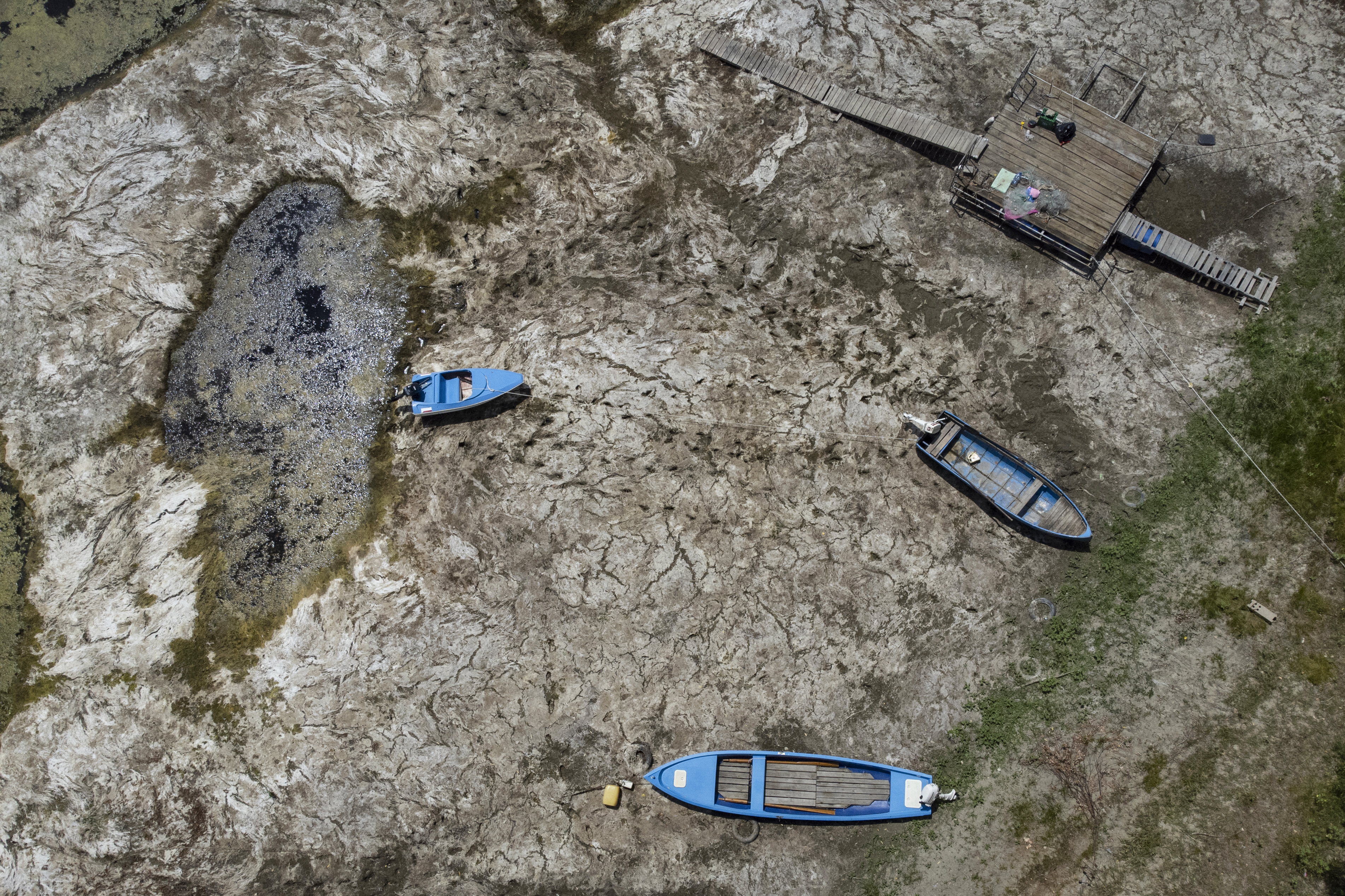 An aerial photograph taken on July 22, 2026 shows boats laying on the dried Danube river bed in front of the Calafat-Vidin bridge, connecting Bulgaria and Romania near the village Antimovo, southeastern Bulgaria. Prolonged drought and hot weather across Europe have pushed water levels along the Danube river to record seasonal lows. (Photo by Nikolay DOYCHINOV / AFP)