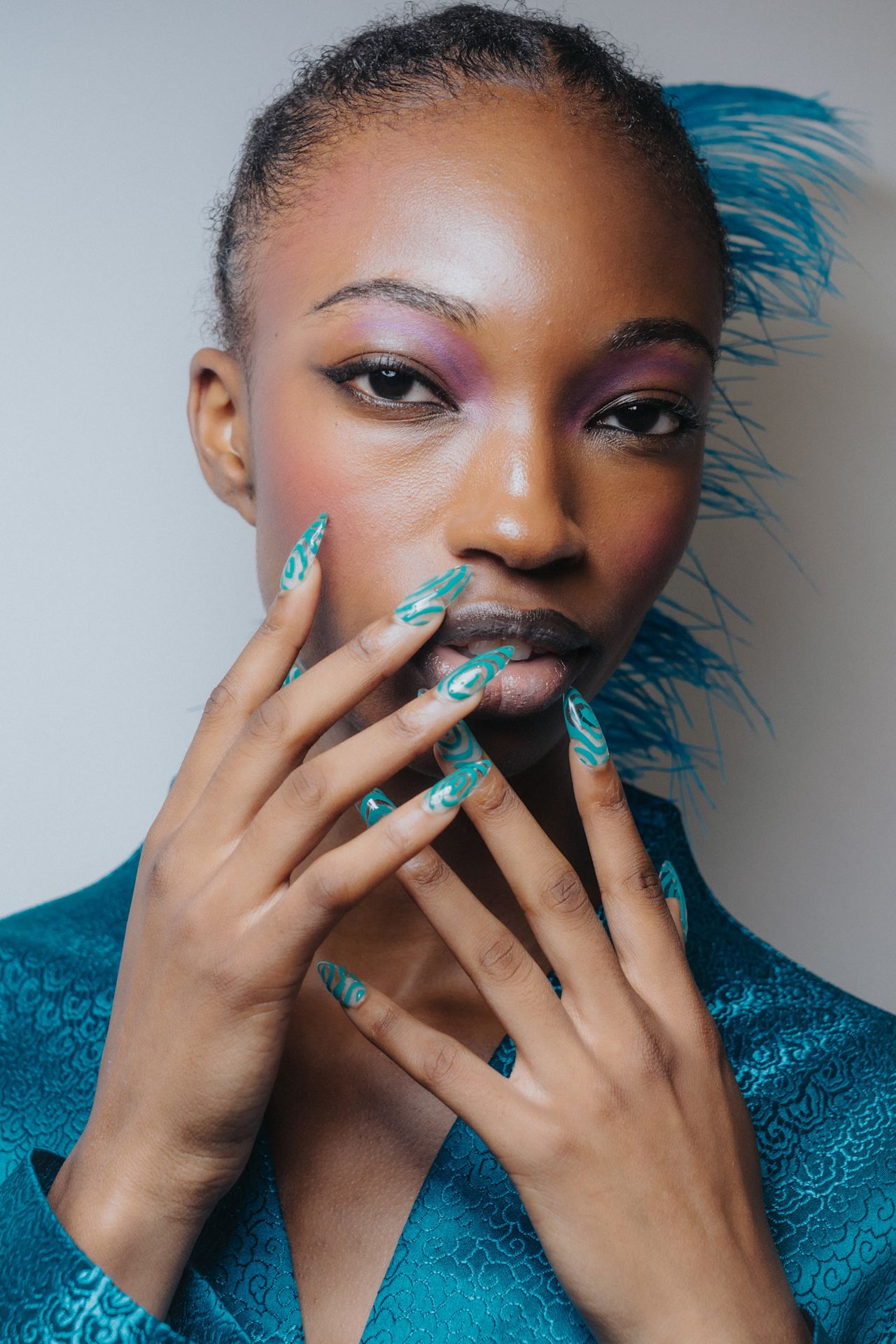 Turquoise almond nails at Kim Shui on a model with feathers in her hair.