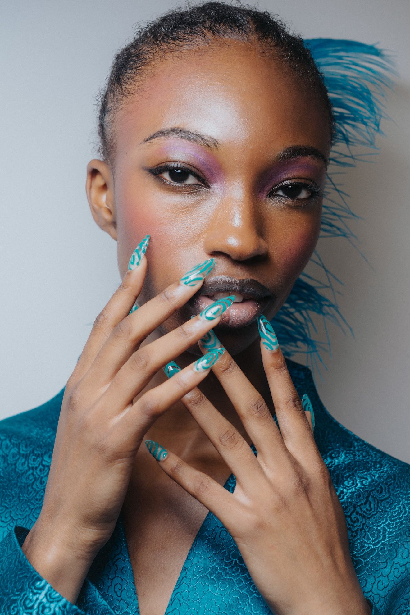 Turquoise almond nails at Kim Shui on a model with feathers in her hair.