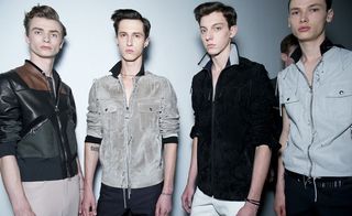 A group of four models posing for the picture with a white backdrop